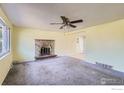 Bright living room features a brick fireplace, ceiling fan, and neutral carpet at 2907 University Ave, Longmont, CO 80503