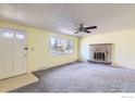 Bright living room with a brick fireplace, a ceiling fan, and a large window at 2907 University Ave, Longmont, CO 80503