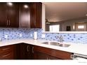 Kitchen featuring stainless steel sink and modern blue tiled backsplash at 2996 S Lamar St, Denver, CO 80227