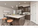 Modern kitchen featuring a large island with seating, dark wood cabinetry, stainless steel appliances, and granite countertops at 636 Morrison Dr, Frederick, CO 80530