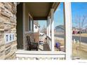 Inviting covered front porch with stone accents, rocking chair and an inviting view of the neighborhood at 781 Rodgers Cir, Platteville, CO 80651