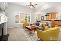 Open-concept living room with a cozy fireplace, a modern sofa, and an adjacent kitchen at 836 Windflower Dr, Longmont, CO 80504