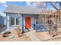 Close-up of the inviting front porch featuring a vibrant orange door and a cozy seating area at 103 Sunset St # A, Longmont, CO 80501