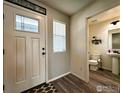 Bright entryway showcases a stylish rug, white door with window, and a glimpse into a half bathroom at 1495 Biffle Ct, Berthoud, CO 80513