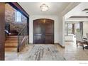 Grand foyer featuring double wooden doors, stone accent wall, stairway, and tile flooring at 1652 Poplar Ave, Boulder, CO 80304