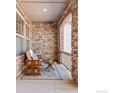 Cozy covered porch featuring stone walls, comfortable seating, and stylish decor at 2232 Sedgwick Ct, Longmont, CO 80503