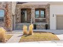 Inviting covered front porch with stone details, decorative wreath, and landscaped garden at 2232 Sedgwick Ct, Longmont, CO 80503