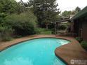 Backyard in-ground pool surrounded by lush greenery, covered patio with furniture at 325 Fox Ct, Boulder, CO 80303