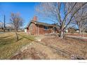 View of the side and front of a charming red brick single-Gathering home with a detached garage and lawn at 4105 Yarrow Ct, Wheat Ridge, CO 80033