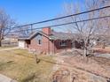 View of the side and front of a charming red brick single-Gathering home with a detached garage and lawn at 4105 Yarrow Ct, Wheat Ridge, CO 80033