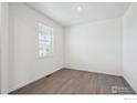 A bright bedroom with neutral walls, wood-look floors, and a window that allows in plenty of natural light at 4115 Marble Dr, Mead, CO 80504