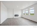 A spacious living room with a fireplace, large windows, and gray wood floors for modern comfort at 4115 Marble Dr, Mead, CO 80504