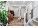 Bright foyer featuring hardwood floors, a stylish rug, staircase, and elegant decor at 4940 Preserve Pl, Firestone, CO 80504