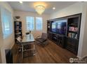 Bright office space featuring a modern glass desk, plush chair, and built-in entertainment center with shelving at 841 Gold Hill Dr, Erie, CO 80516