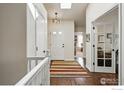 Inviting entryway with hardwood floors and natural light. Featuring a decorative rug and a glass french door office at 1602 Oak Ridge Ln, Longmont, CO 80501