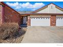 Charming brick home with a two-car garage, complemented by mature landscaping at 1602 Oak Ridge Ln, Longmont, CO 80501