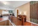 Stylish hallway with hardwood floors, wrought iron railings and a view into the living area and fireplace at 1614 Hideaway Ct, Longmont, CO 80503