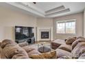 Inviting living room features a cozy fireplace, tray ceiling, and comfortable seating area with natural light at 17012 Lipan St, Broomfield, CO 80023