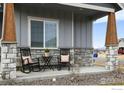 Inviting front porch featuring stone accents, rocking chairs, and wood columns at 213 Rocking Chair Dr, Berthoud, CO 80513