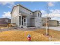 Two-story gray home featuring a three-car garage, and landscaped front yard at 2405 Horse Shoe Cir, Fort Lupton, CO 80621