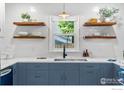 Stylish kitchen featuring blue cabinets, floating shelves, and a farmhouse sink with a window view at 2625 6Th St, Boulder, CO 80304