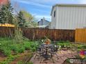 Cozy backyard patio with flagstone and a black metal table and chairs amidst lush landscaping and a tall wood fence at 339 S Hoover Ave, Louisville, CO 80027