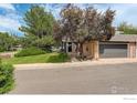 Charming home exterior features mature trees, a lush lawn and attached two-car garage at 4996 Clubhouse Cir, Boulder, CO 80301