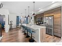 Open kitchen with island, breakfast bar, stainless steel appliances, and wood floors at 5678 W 10Th Pl, Lakewood, CO 80214