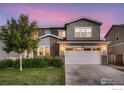 Two-car garage home exterior with manicured lawn, stone details, and modern lighting at 6894 E 133Rd Pl, Thornton, CO 80602