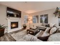 Cozy living room features a fireplace, large sectional sofa, and ample natural light from large windows at 6894 E 133Rd Pl, Thornton, CO 80602