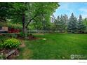 Large backyard with mature trees, green grass, play structure, and stone retaining wall at 835 Linden Ave, Boulder, CO 80304