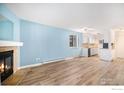 Spacious living area featuring new wood floors, a cozy fireplace, a view of the kitchen, and natural light at 14760 E Kentucky Dr # 312, Aurora, CO 80012