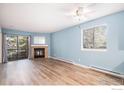 Bright living room featuring wood floors, modern ceiling fan, fireplace, and sliding glass doors to the outside deck at 14760 E Kentucky Dr # 312, Aurora, CO 80012