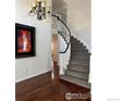 Elegant carpeted staircase with white railing and dark wood trim, illuminated by a chandelier, enhancing the home's interior at 1618 Garnet St, Broomfield, CO 80020