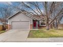 Inviting home exterior with a two-car garage, well-kept lawn, and a vibrant red front door at 1624 Foster Dr, Longmont, CO 80501