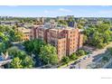 Aerial shot of a multi-story brick building surrounded by lush greenery in an urban environment on a sunny day at 1630 N Clarkson St # 110, Denver, CO 80218