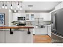 Stylish kitchen featuring white cabinets, stainless steel appliances, and a butcher block bar top island with unique lighting at 1630 N Clarkson St # 110, Denver, CO 80218