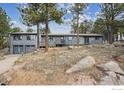 Exterior of home featuring two-car garage, deck access and mature pines at 191 Alder Ln, Boulder, CO 80304