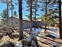 View of home through mature trees, deck access and some snow at 191 Alder Ln, Boulder, CO 80304