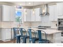 Bright kitchen featuring white cabinets, stainless steel appliances, an island with barstool seating, and pendant lighting at 803 Old Wagon Trail Cir, Lafayette, CO 80026