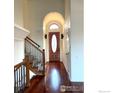 Inviting foyer with hardwood floors, archway, and a beautiful wood and iron staircase at 10895 W Half Moon Pass, Littleton, CO 80127