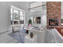 Bright living room with a brick fireplace, large windows, and a cozy seating area at 10895 W Half Moon Pass, Littleton, CO 80127