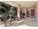 Inviting covered front porch with brick accents, chairs and a view of mature evergreens at 109 Blue Heron Ct, Mead, CO 80542