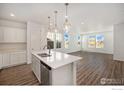 Bright kitchen features a stainless steel dishwasher, white cabinetry, and an island with a sink and quartz countertop at 186 Washington St, Erie, CO 80516