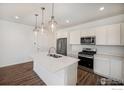 Modern kitchen with white cabinets, stainless steel appliances, quartz countertops, and stylish pendant lighting at 186 Washington St, Erie, CO 80516