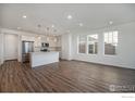 Open-concept living room and kitchen featuring hardwood floors, stainless steel appliances, and ample natural light at 186 Washington St, Erie, CO 80516