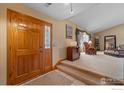 Welcoming foyer with wood door, tile flooring, and view of living room at 2418 Maplewood E Cir, Longmont, CO 80503