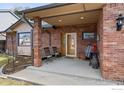 Charming covered front porch with brick columns and comfortable seating area at 2418 Maplewood E Cir, Longmont, CO 80503