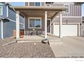 Covered front porch with seating area and steps leading to the entrance door with wreath at 2425 Mountain Sky Dr, Fort Lupton, CO 80621