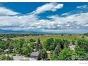 An aerial view of a property shows lush landscape, fields, and trees under a blue sky at 4705 Chatham St, Boulder, CO 80301
